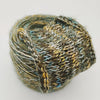 A ball of variegated yarn with a chunky knit texture, featuring mixed colors of olive green, mustard yellow, light blue, and white, set against a plain light gray background.