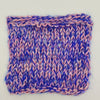 A square knitted swatch of variegated yarn in purple and pink, showing a ribbed texture and finished edges, photographed on a plain light background.