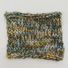 A square knitted swatch of variegated yarn with a textured v-stitch pattern, featuring colors of olive green, mustard yellow, light blue, and white, set against a plain white background.
