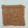 A square knitted fabric swatch in a warm tan and light brown variegated yarn, showing a ribbed knit texture, set against a plain white background.