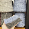 Soft baby alpaca boucle yarn by Stock Igea, featuring thick, textured fibers in natural cream color, ideal for cozy knitting projects.